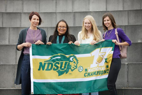NDSU Educators and Students standing on the SBS steps holding their NDSU banner and smiling. 